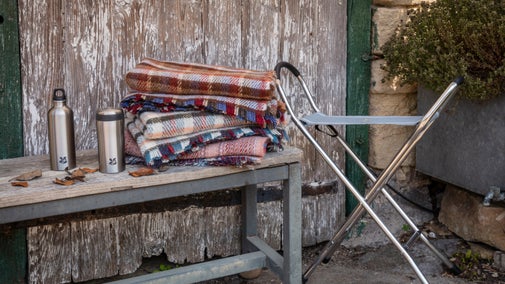 Colourful picnic rugs, drinking flasks and a foldable chair